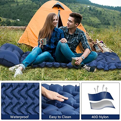 Paar sitzt auf einer blauen Outdoor-Matratze vor einem Zelt.